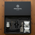 Protocol Kit Co. survival kit with knife, fire starter, and other tools on a wooden surface